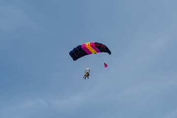 Parachutists: Instructor and Beginner with Blue Parachute against Clear Blue Sky