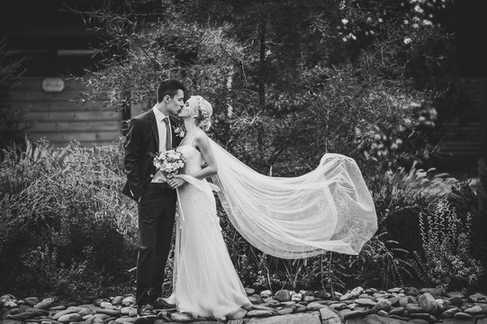 Bride and groom kissing outdoors. Black and white photo.