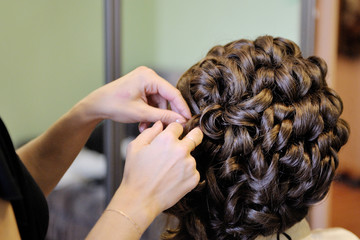 The stylist prepares the bride for the wedding. Hair styling. Morning gathering of the bride.