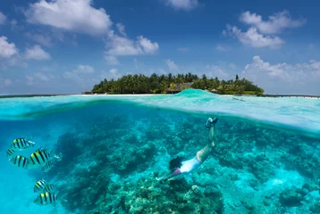 Rolgordijnen Frau schnorchelt über Korallen und tropischen Fischen vor einer Insel auf den Malediven © moofushi