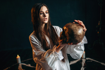 Woman holds human skull in hand, dark magic, witch