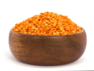 Red raw lentils in a wooden bowl. Isolated on white background