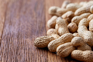 Unpeeled peanuts on a wooden background, top view, selective focus, shallow depth of field.