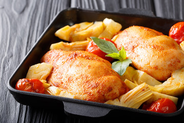 Organic food: a serving of chicken breast with artichokes and tomatoes close-up on a plate. horizontal