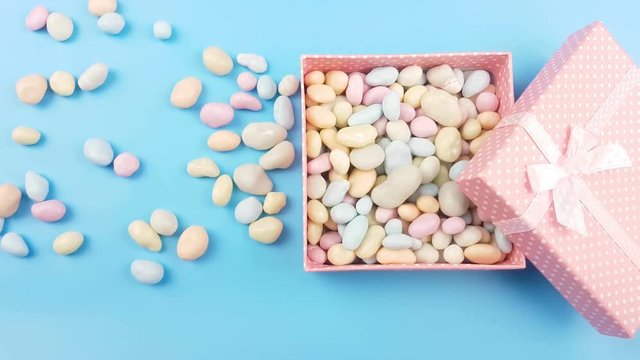 Nice pastel color candy or stone in gift pink box on blye surface.
