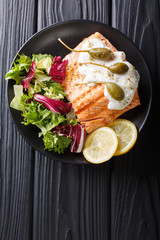 salmon piccata with capers and fresh mix salad closeup. Vertical top view