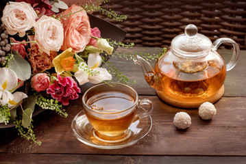 a glass teapot with a glass mug and a bouquet of flowers on the breakfast table