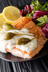 Salmon piccata with fresh mix salad closeup. vertical