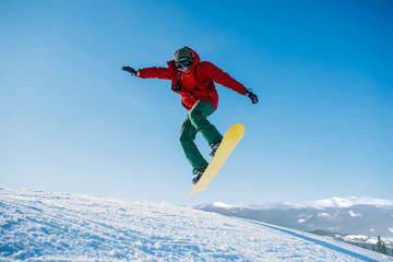 Naklejka na ściany i meble Snowboarder makes a jump on speed slope
