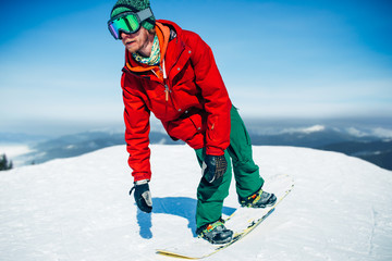 Fototapeta na wymiar Snowboarder in glasses poses with board in hands