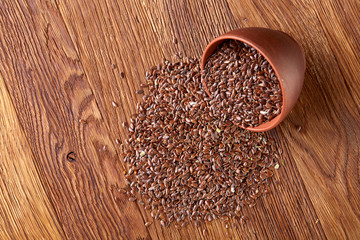 An overturned ceramic bowl with linseeds on a rustic background, close-up, shallow depth of field, selective focus