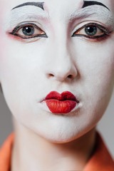 Woman in geisha makeup and a traditional Japanese kimono. Studio, Indoor.