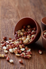 Two ceramic bowls with raw peanuts mix isolated over rustic wooden backround, top view, close-up.