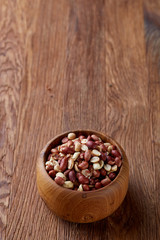 Two ceramic bowls with raw peanuts mix isolated over rustic wooden backround, top view, close-up.
