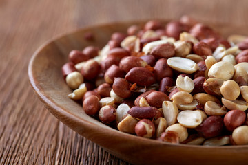 Two ceramic bowls with raw peanuts mix isolated over rustic wooden backround, top view, close-up.
