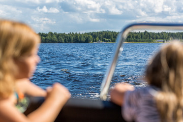 Two young girls look to lake from motor boat