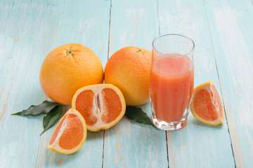 Grapefruit juice and ripe grapefruits on a wooden background