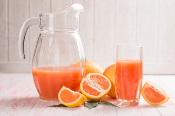 Grapefruit juice and ripe grapefruits on a wooden background