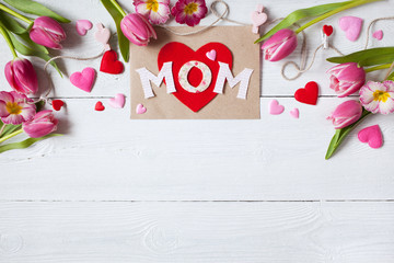 Background for congratulations for Mother's Day with greeting card, hearts and pink tulips, primula