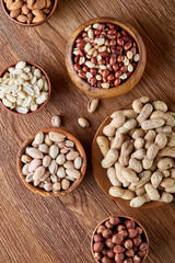 A composition from different varieties of nuts in a wooden bowls on rustic background, close-up, shallow depth of field