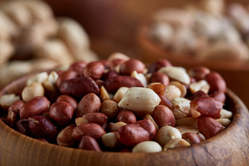A composition from different varieties of nuts in a wooden bowls on rustic background, close-up, shallow depth of field