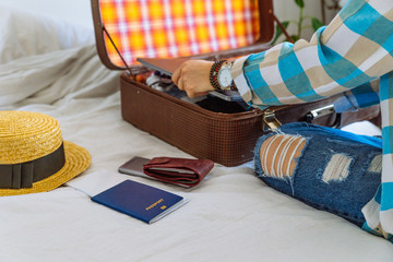 woman hands with watch put clothes in suitcase. travel concept. copy space. biometric passport laptop wallet