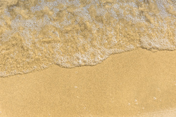 Soft wave on a sandy beach - close-up, top view