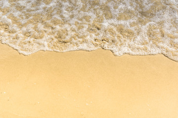 Fototapeta na wymiar Soft wave on a sandy beach - close-up, top view