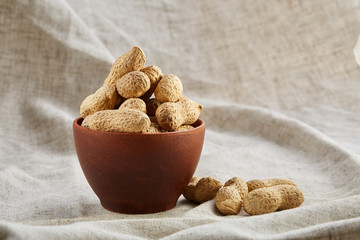 Salted pistachios on a wooden plate over white background, top view, close-up, selective focus.