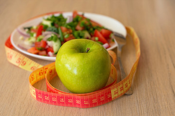 healthy eating, dieting, slimming and weigh loss concept - close up of green apple, measuring tape...