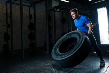 Obraz na płótnie Canvas a photo of a strong bodybuilder with a heavy wheel in the gym
