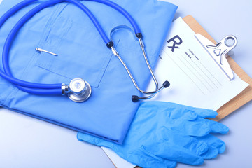 Medical stethoscope, gloves, RX prescription, and blue doctor uniform closeup. Medical help or insurance concept. Cardiology care, health, protection and prevention.