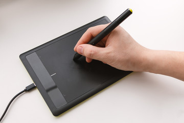 Men's hand draws on a graphics tablet using a stylus
