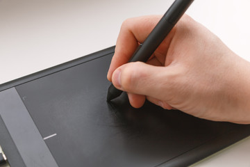 Men's hand draws on a graphics tablet using a stylus
