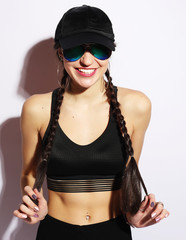 Portrait of a young woman in a cap and sunglasses over white background.