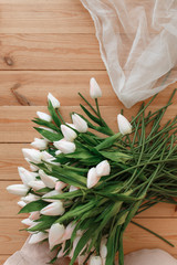 white tulips on natural wooden background topview. Spring melody