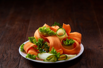 Artistically served vegetable salad with carrot, cucumber, letucce over wooden background,...