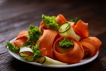 Artistically served vegetable salad with carrot, cucumber, letucce over wooden background,...