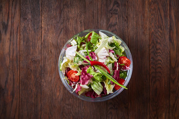 Fresh vegetable salad and ripe veggies on cutting board over wooden background, close up, selective focus