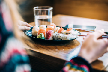 Crop woman eating sushi