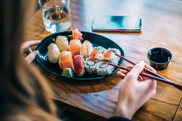 Crop woman eating sushi