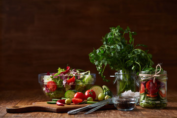 Delicious vegetable salad in jar and fresh veggies on cutting board on table, selective focus, close-up