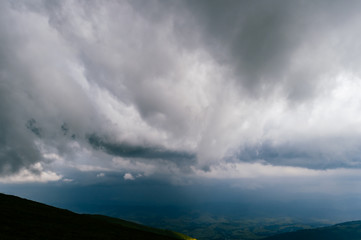 Fototapeta premium Storm rainy clouds above mountains. Apocalypse fantasy fabulous sky. Beautiful windy dramatic cloudscape at nature. Picturesque scenic view outdoor. Travel in wild territory. Discover rocky hills.