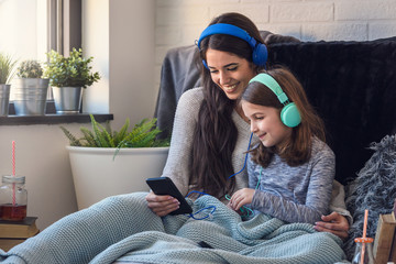 Obraz premium Girls having fun at home, listening music over smart phone. Family quality time