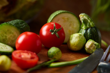Fresh vegetable salad and ripe veggies on cutting board over wooden background, close up, selective focus