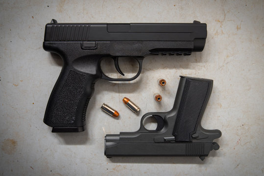 Two Handguns on Concrete Floor with Bullets