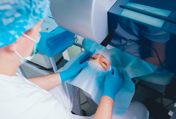 Laser vision correction. A patient and team of surgeons in the operating room during ophthalmic...