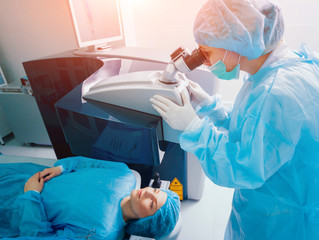 Laser vision correction. A patient and team of surgeons in the operating room during ophthalmic...