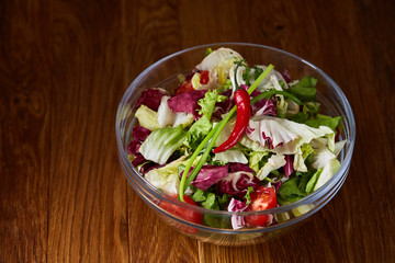 Fresh vegetable salad and ripe veggies on cutting board over wooden background, close up, selective focus