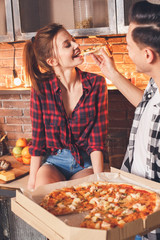 Closeup photo. Smiling man give one piece of pizza his wife